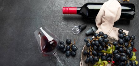 Téléchargez les photos : Une photo aérienne de verres de vin rouge avec une bouteille, des raisins, et un bouchon de liège vintage et des bouchons de liège, prise d'en haut sur un fond sombre. Vue de dessus. Panorama avec espace de copie. - en image libre de droit