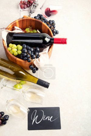 Photo for Wine Tasting. An overhead photo of glasses of red and white wine with a bottle, grapes, and a vintage corkscew and corks, shot from above on a light background. - Royalty Free Image
