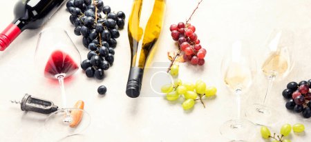 Téléchargez les photos : Dégustation de vin. Une photo aérienne de verres de vin rouge et blanc avec une bouteille, des raisins, et un bouchon de liège vintage et des bouchons de liège, prise d'en haut sur un fond clair. Panorama. - en image libre de droit
