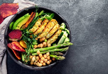 Photo for Vegan buddha bowl. Bowl with  vegetables, Zucchini fritters and vegetables chips. Dark background. Healthy eating concept. Top view - Royalty Free Image