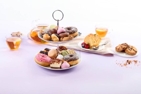 Foto de Té tradicional inglés. Té de la tarde con selección de dulces sobre fondo violeta. Concepto de vacaciones - Imagen libre de derechos