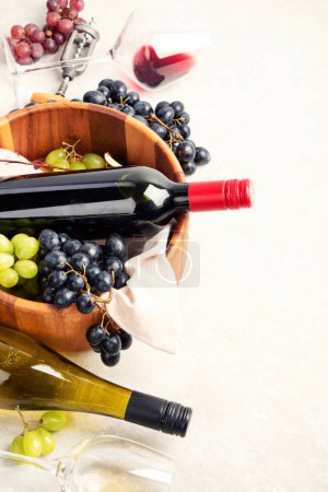 Téléchargez les photos : Dégustation de vin. Une photo aérienne de verres de vin rouge et blanc avec une bouteille, des raisins, et un bouchon de liège vintage et des bouchons de liège, prise d'en haut sur un fond clair. - en image libre de droit