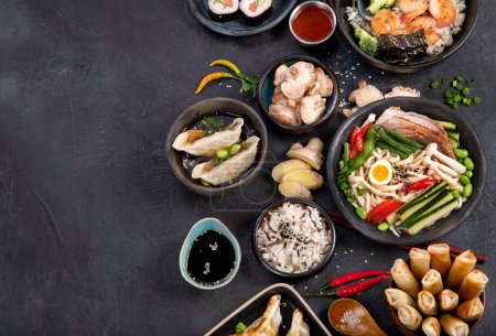 Téléchargez les photos : Nourriture asiatique traditionnelle. Divers repas asiatiques sur fond sombre. Plats variés de la cuisine traditionnelle. Vue du dessus, espace de copie - en image libre de droit