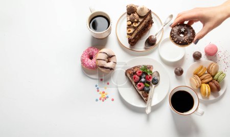 Foto de Mesa con varias galletas, rosquillas, pasteles, tartas de queso y tazas de café sobre fondo blanco. Deliciosa mesa de postres. Vista superior, plano, espacio para copiar - Imagen libre de derechos