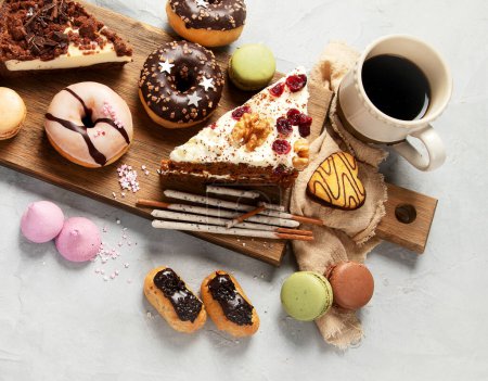 Photo for Selection of various cake pieces, macaroons, meringues, cookies and donuts on a wooden desk on a light background. Top view. Confectionery background. - Royalty Free Image