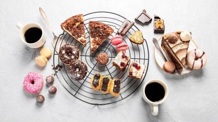 Foto de Mesa con varias galletas, rosquillas, pasteles y tazas de café en el fondo ligero. Vista superior. - Imagen libre de derechos