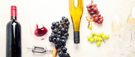 Téléchargez les photos : Dégustation de vin. Une photo aérienne de verres de vin rouge et blanc avec une bouteille, des raisins, et un bouchon de liège vintage et des bouchons de liège, prise d'en haut sur un fond clair. Panorama. - en image libre de droit