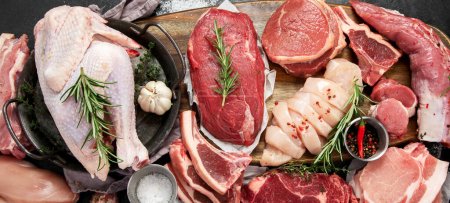 Téléchargez les photos : Différents types de viande crue - bœuf, porc, agneau, poulet sur fond sombre. Vue du dessus - en image libre de droit