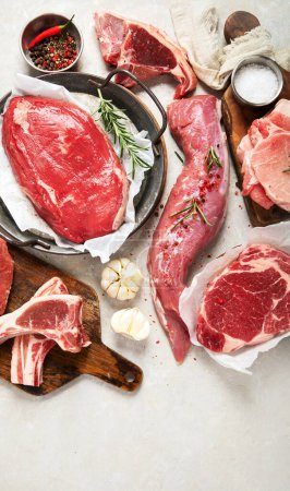 Téléchargez les photos : Différents types de viande fraîche : porc, bœuf et poulet sur fond gris. Vue du dessus. - en image libre de droit