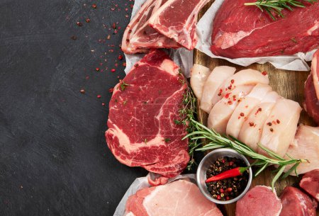 Photo for Different types of raw meat - beef, pork, lamb, chicken on dark background. Top view, copy space - Royalty Free Image