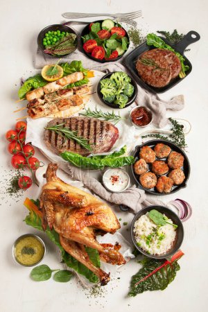 Téléchargez les photos : Différents types de viande cuite saine - bœuf, porc, poulet sur un fond léger avec riz, légumes et salade. Vue du dessus. - en image libre de droit