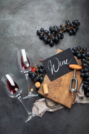 Foto de Una foto aérea de copas de vino tinto con una botella, uvas, y un corcho vintage y corchos, disparados desde arriba sobre un fondo oscuro. Vista superior. - Imagen libre de derechos