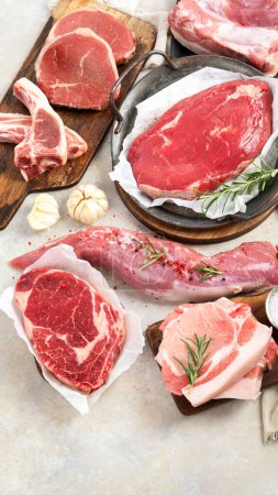 Foto de Varios tipos de carne fresca: cerdo, ternera y pollo sobre un fondo gris. Vista superior. - Imagen libre de derechos
