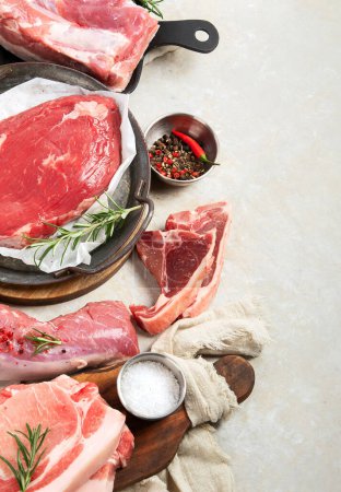 Foto de Varios tipos de carne fresca: cerdo, ternera y pollo sobre un fondo gris. Vista superior. - Imagen libre de derechos