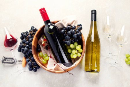 Téléchargez les photos : Dégustation de vin. Une photo aérienne de verres de vin rouge et blanc avec une bouteille, des raisins, et un bouchon de liège vintage et des bouchons de liège, prise d'en haut sur un fond clair. - en image libre de droit