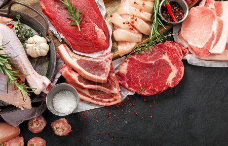 Photo for Different types of raw meat - beef, pork, lamb, chicken on dark background. Top view, copy space - Royalty Free Image