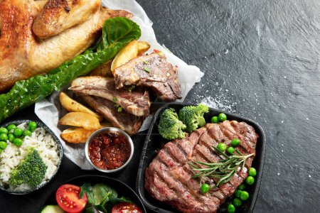 Photo for Various types of healthy cooked meat - beef, pork, chicken on a dark background with vegetables and salad. Top view. - Royalty Free Image
