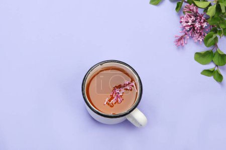 Foto de Lilac flowers with cup of tea on colourful background. Atmospheric summer concept. Top view, flat lay, copy space - Imagen libre de derechos