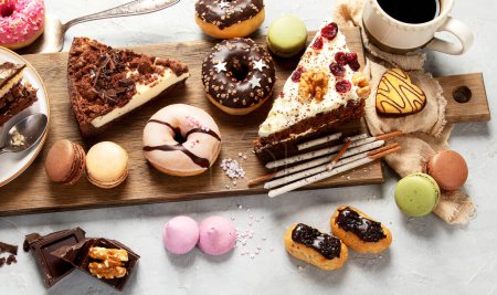Téléchargez les photos : Sélection de différentes pièces de gâteau, macarons, meringues, biscuits et beignets sur un bureau en bois sur un fond clair. Vue de dessus. Contexte de la confiserie. - en image libre de droit