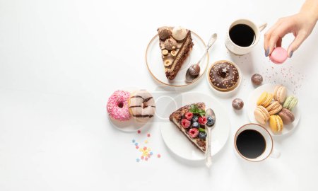 Foto de Mesa con varias galletas, rosquillas, pasteles, tartas de queso y tazas de café sobre fondo blanco. Deliciosa mesa de postres. Vista superior, plano, espacio para copiar - Imagen libre de derechos