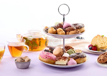 Traditioneller englischer Tee. Nachmittagstee mit einer Auswahl an Süßigkeiten auf violettem Hintergrund. Urlaubskonzept