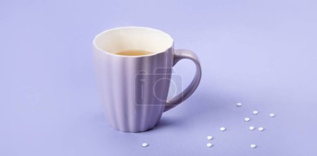 Téléchargez les photos : A cup of tea with sweetener. Artificial sugar on a violet background, top view. Panorama. - en image libre de droit