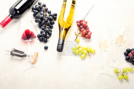 Photo for Wine Tasting. An overhead photo of glasses of red and white wine with a bottle, grapes, and a vintage corkscew and corks, shot from above on a light background. - Royalty Free Image
