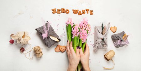 Foto de Zero waste Valentine's Day concept. Eco-friendly gift cloth wrapping in Furoshiki style, homemade sweets and cookies as gift ideas, spring flowers. Top view. - Imagen libre de derechos