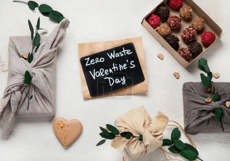 Foto de Zero waste Valentine's Day concept. Eco-friendly gift cloth wrapping in Furoshiki style, homemade sweets and cookies as gift ideas on white background. Top view or flat lay. - Imagen libre de derechos