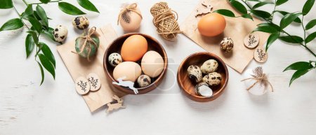 Foto de Easter eggs decorated with natural materials on a white background. Top view. Minimalistic decor for Easter. Panorama with copy space. - Imagen libre de derechos