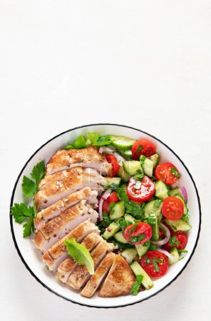 Photo for Grilled chicken breast, fillet and fresh vegetable salad of lettuce, arugula, spinach, cucumber and tomato on a white background. Healthy lunch menu. Diet food. Top view. - Royalty Free Image