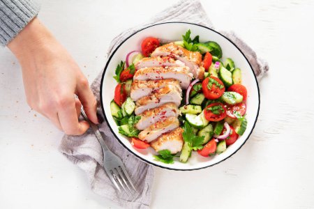 Téléchargez les photos : Grilled chicken breast, fillet and fresh vegetable salad of lettuce, arugula, spinach, cucumber and tomato on a white background. Healthy lunch menu. Diet food. Top view. - en image libre de droit