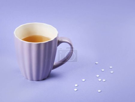 Téléchargez les photos : Tasse de thé avec édulcorant. Sucre artificiel sur fond violet, vue du dessus. - en image libre de droit