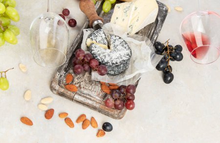Téléchargez les photos : Pink and red wine served with cheeses, nuts, grapes and glasses of wine. Delicious food wine snacks assorted served on boards. Flat lay on a white background. Panorama with copy space. - en image libre de droit
