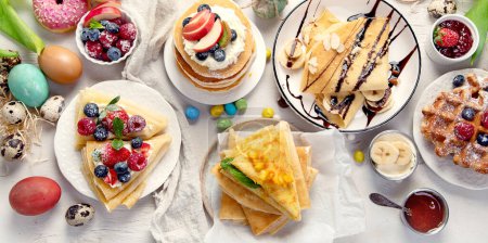Photo for Easter sweet dessert table. Pancakes, crepes, waffles and donuts  with fresh berries, nuts and topping.   Easter traditional natural colorful eggs. Top view, flat lay - Royalty Free Image