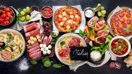 Téléchargez les photos : Italian food dishes on dark background. Traditional italian cuisine  concept. Dishes and appetizers of indeed cuisine. Mideterranean diet food high in vitamin and antioxidants. Top view - en image libre de droit