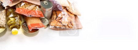 Photo for Food donations with pasta, rice, oil, peanut butter, canned food, jam and other  on light background, panorama, banner  with copy space. Food donations or delivery concept. - Royalty Free Image