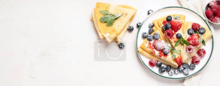 Foto de Healthy breakfast, homemade traditional crepes or pancakes with fresh berries, morning light background. Copy space top view, panorama, banner - Imagen libre de derechos