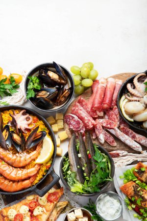 Foto de Assortment various Mediterranean food - fish, octopus, shrimp,  seafood, mussels, sauces, pasta, pizza on a white background. Top view. - Imagen libre de derechos