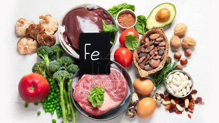 Foto de Food containing natural iron. Fe: Liver, avocado, broccoli, spinach, parsley, beans, nuts, on a white background. Top view. - Imagen libre de derechos