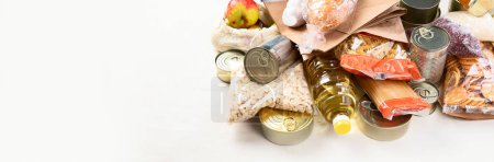 Téléchargez les photos : Food donations with pasta, rice, oil, peanut butter, canned food, jam and other  on light background, panorama, banner with copy space. Food donations or delivery concept. - en image libre de droit