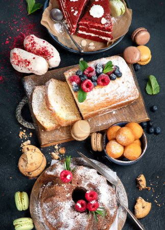 Verschiedene Desserts auf dunklem Hintergrund. Köstliche süße Desserttafel mit Pfund Kuchen, Schokolade und rotem Samt Kuchen. Urlaubssüß-Konzept. Ansicht von oben