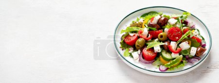 Foto de Greek salad of fresh cucumber, tomato, sweet pepper, lettuce, red onion, feta cheese and olives with olive oil on a white background. Healthy food, top view. Panorama with copy space. - Imagen libre de derechos