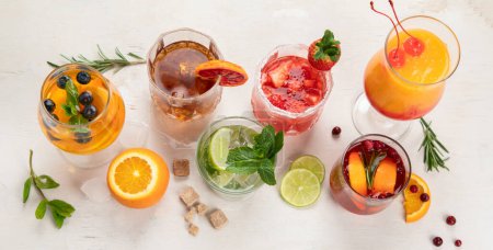 Téléchargez les photos : Différents délicieux cocktails sur la table. Coctail alcoolisé avec fruits, herbes et glace sur fond blanc. Vue du dessus. - en image libre de droit