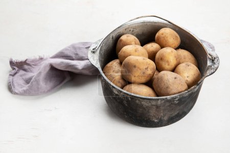 Foto de Comida cruda de papa. Patatas frescas en una olla vieja sobre un fondo blanco. Vista superior - Imagen libre de derechos