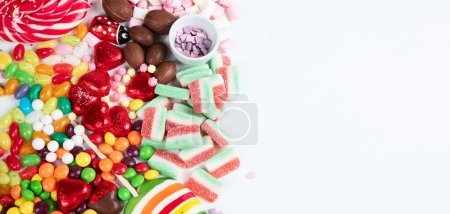 Téléchargez les photos : Assortiment de bonbons colorés sur un fond blanc. Vue de dessus. Panorama avec espace de copie. - en image libre de droit