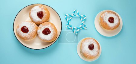 Foto de Hanukkah donas dulces sufganiyot (donas tradicionales) con mermelada de jalea de frutas y velas blancas sobre fondo de papel azul. vacaciones judías concepto de Hanukkah. - Imagen libre de derechos