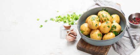 Photo for Young boiled potatoes on the plate with parsley and onion on the board. White background. Top view. Panorama with copy space. - Royalty Free Image