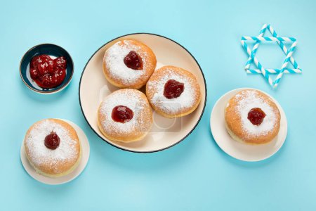 Photo for Hanukkah sweet doughnuts sufganiyot (traditional donuts) with fruit jelly jam and white candles on blue paper background. Jewish holiday Hanukkah concept. - Royalty Free Image