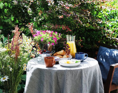 Photo for Continental breakfast on the garden table. Country lifestyle or weekend morning concept. Peaceful rural scenery. - Royalty Free Image